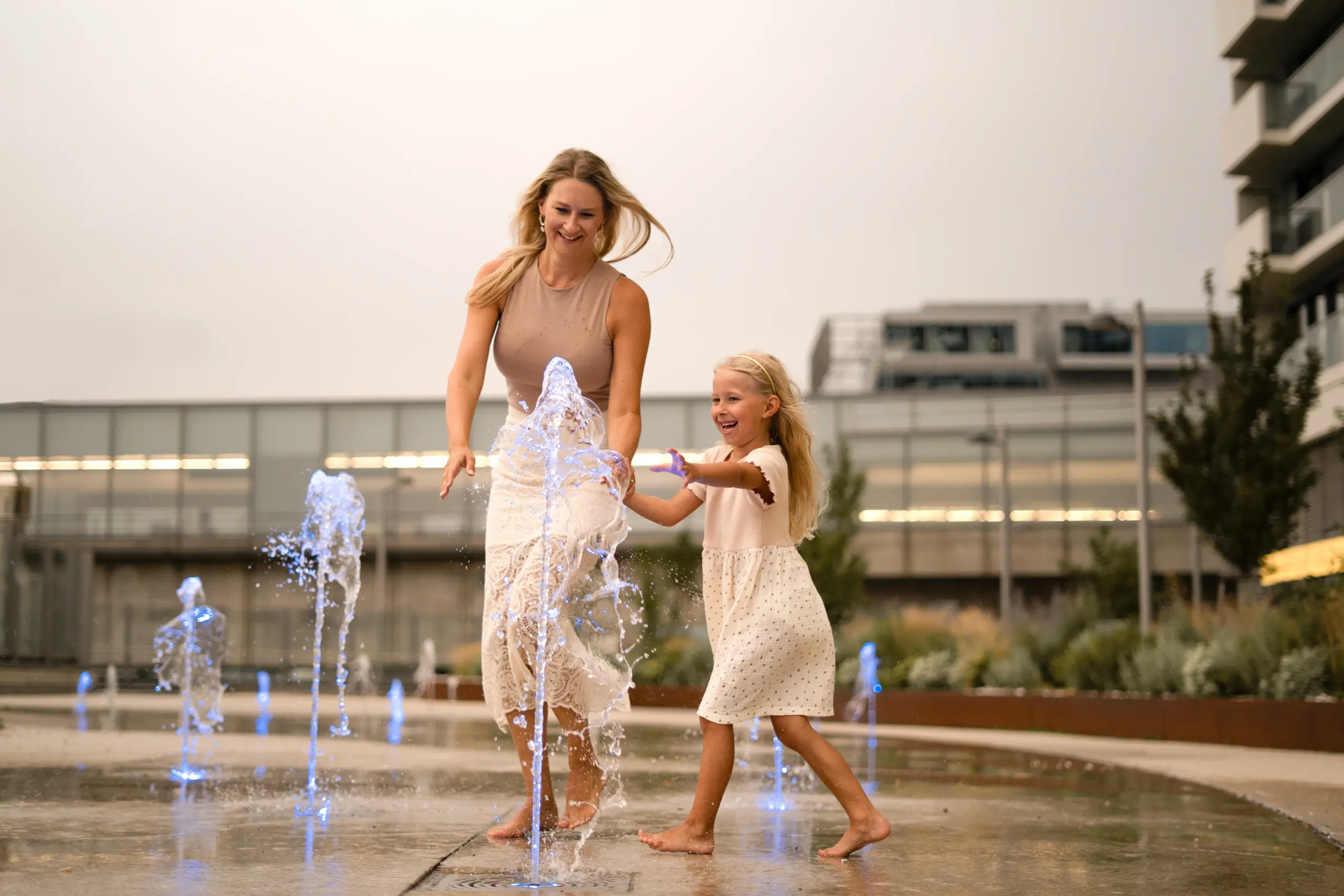 Mutter und Tochter (5 Jahre) laufen fröhlich im Sommer durch einen Wasserpark.