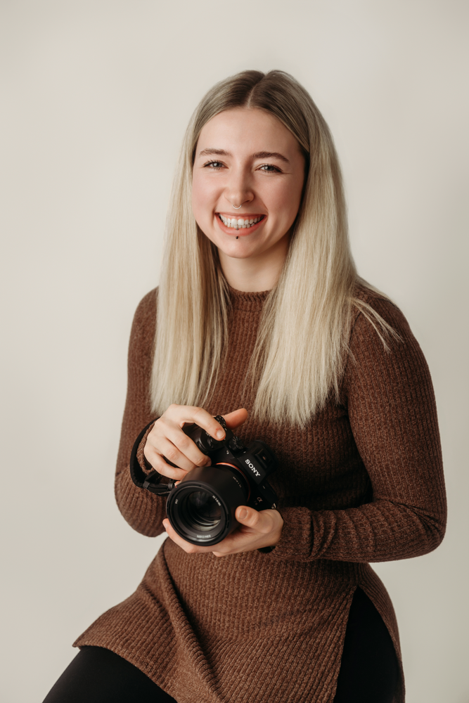 Isabella Suppan Fotografie mit ihrer Sony Kamera in der Hand. Es ist ein Studio Porträt.